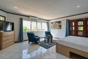 a bedroom with a bed and two chairs and a television at Private Beach Ocean Front Boat Dock Tiki Bar in Savaneta