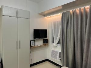 uma sala de estar com televisão e janela em Morgan Suites Executive Residences em Manila