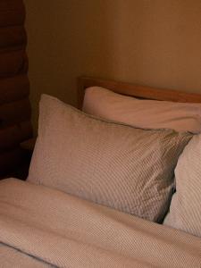 uma cama com lençóis brancos e uma almofada em Kilomètre 42 em Val-David