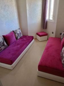 ein Wohnzimmer mit einem lila Sofa und 2 Hockern in der Unterkunft soleil d'chamalo in Fnideq