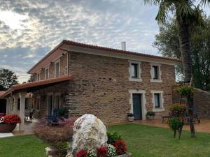 ein Backsteinhaus mit einem Stein davor in der Unterkunft Casa Fontes Rosas in Touro