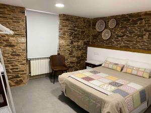 1 dormitorio con cama y pared de piedra en Casa Fontes Rosas en Touro