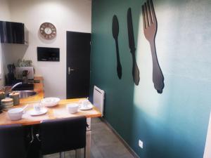 una cocina con tenedor y cuchillo en la pared en Le Cocon d'Aurore, en Reims