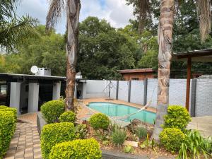 a swimming pool with a hammock between two palm trees at Bridgelamour Guest House in Hartbeespoort