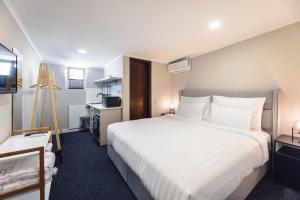 a bedroom with a large white bed and a kitchen at Salve in Tbilisi City