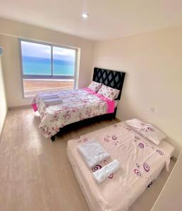 duas camas num quarto com o oceano ao fundo em Tú hogar frente al mar em Lima