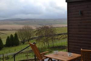 a wooden table and chairs on a porch with a view at LetAway - The Warren Lodge at Ashes Farm in Settle