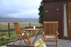 a wooden table and two chairs next to a house at LetAway - The Hive Lodge at Ashes Farm in Settle