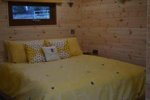 a bedroom with a bed with yellow sheets and pillows at LetAway - The Hive Lodge at Ashes Farm in Settle