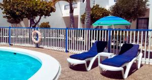 two chairs and an umbrella next to a swimming pool at Ocean & Pool view Puerto del Carmen in Puerto del Carmen