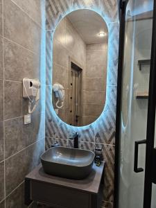 La salle de bains est pourvue d'un lavabo et d'un miroir. dans l'établissement DeLuxe Apartments, à Almaty