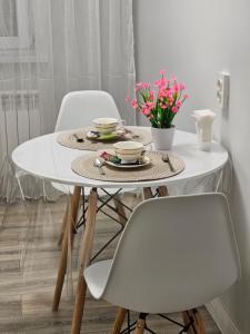 uma mesa de jantar branca com cadeiras e flores em DeLuxe Apartments em Almaty