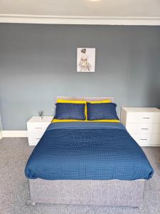 a bedroom with a blue bed with blue and yellow pillows at Spacious large room 001 in Nottingham