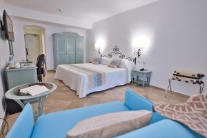 ポルト・コンテにあるエル ファロ ホテル ＆ スパのベッドルーム(ベッド1台、青いソファ付)