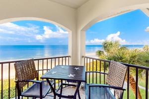 una mesa y sillas en un balcón con vistas al océano en Tortugas De Mar, Unit 303B en Clearwater Beach