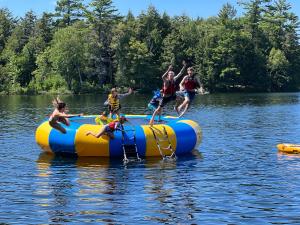 a group of people jumping off anlatable raft on the water at Walker Lake Resort in Huntsville