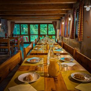 une longue table en bois avec des assiettes de nourriture dans l'établissement Rifugio Aleve, à Castello