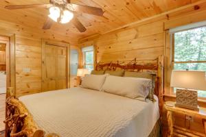 Cette cabane en rondins comprend un lit et un ventilateur de plafond. dans l'établissement Blue Ridge Cabin Rental with Hot Tub and Creek Access!, à Blue Ridge