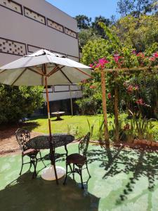 a table and chairs and an umbrella in the water at Pousada la colline in Santo Antônio do Pinhal