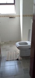 a bathroom with a toilet and a window and a rug at Shawmut suites in Nakuru
