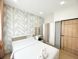 um quarto com uma cama branca e toalhas em Phattharasaya Home em Udon Thani