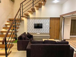 a living room with a couch and a tv at Modern villa 4BR, Lawn & Mini Pool in Belagavi in Shāhāpur