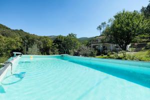 une grande piscine bleue avec une colline en arrière-plan dans l'établissement VILLA EMILY, à Framura