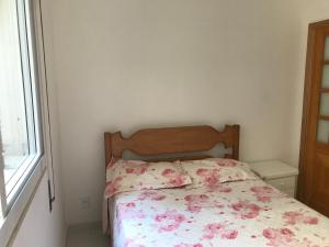 1 dormitorio con 1 cama con colcha de flores y ventana en COPACABANA 2 Quartos e Sala, QUADRA DA PRAIA no Posto 6, en Río de Janeiro