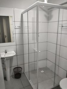 uma casa de banho com uma cabina de duche em vidro e um lavatório. em Pousada Flor de Mãe em Volta Redonda