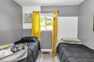 - une chambre avec 2 lits et une fenêtre avec des rideaux jaunes dans l'établissement Cozy Retreat in Cincinnati home, à Cincinnati