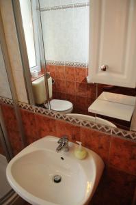 a bathroom with a sink and a mirror and a toilet at Apartman Bella Hotel in Siófok