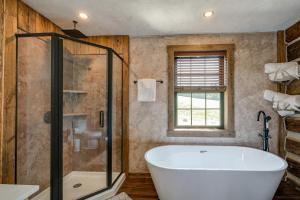 ein Badezimmer mit Badewanne und Glasdusche in der Unterkunft Bedford Cabin with Porch, 5 Mi to Historic District! in Bedford + 18 Fotos