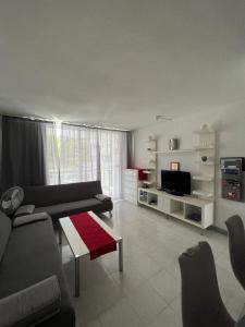 uma sala de estar com um sofá e uma televisão em Apart Hotel Ponderosa em Playa de las Americas