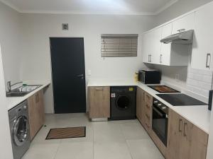 a white kitchen with a washer and dryer in it at Fun modern two bed apartment in fourways in Sandton