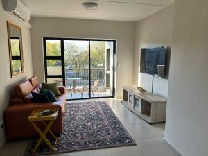 a living room with a couch and a tv at Fun modern two bed apartment in fourways in Sandton