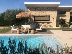 una piscina con due sedie e un ombrellone e un pianoforte di La parenthèse a Aubérives-sur-Varèze
