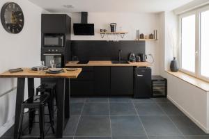 a kitchen with black cabinets and a counter with a table at UNE PARENTHESE ARDENNAISE in Charleville-Mézières