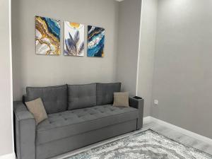 een woonkamer met een grijze bank en 3 schilderijen bij Sat City Deluxe in Astana