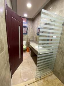 La salle de bains est pourvue d'une porte en verre et d'un lavabo. dans l'établissement Cozy Stylish Studio with workspace, à Assouan