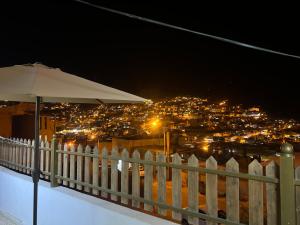 a white fence with an umbrella and a city at night at Desert Moon in Wadi Musa