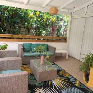 une terrasse avec un canapé, des chaises et des plantes dans l'établissement Appartement "grand Hibiscus" jardin privé, au Lamentin