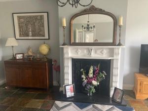 a living room with a fireplace with a mirror and flowers at The Stay @ 155 