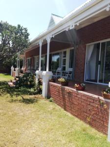 a brick house with a porch with chairs on it at Oppikrom Rivertide 36 in St Francis Bay