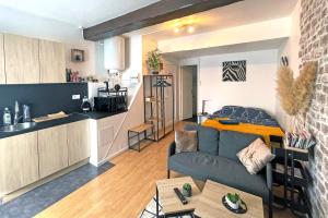 a living room with a couch and a kitchen with a bed at Escapade Moretaine - Cosy Studio in Moret-sur-Loing