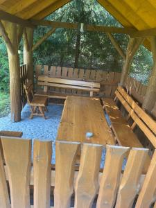 uma mesa de madeira e bancos num pavilhão em Zakątek przy lesie 