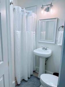 uma casa de banho com uma cortina de chuveiro branca e um lavatório. em Walk To Duke Campus! 3 Bedroom In Trinity Park! em Durham