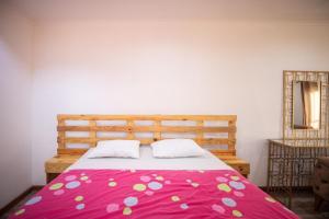 1 dormitorio con 1 cama con manta rosa y blanca en Guesthouse WF, en São Tomé