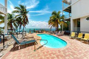 a swimming pool with chairs and the ocean in the background at Cool Water Retreat in Marathon