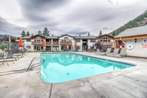 a swimming pool with chairs and umbrellas at a resort at Icicle Village Resort 401 Aspen Abode in Leavenworth