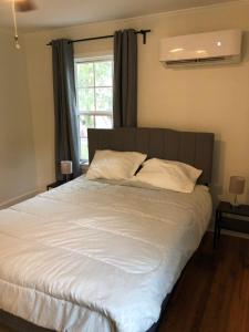 - une chambre avec un lit doté de draps blancs et une fenêtre dans l'établissement Renovated Cottage Minutes From Downtown, à Durham